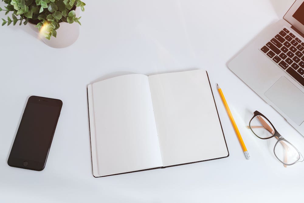 laptop, notebook, pencil and glasses on a table